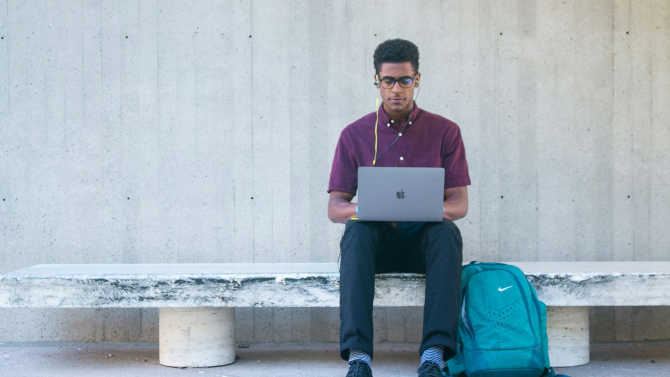 a man sitting on a bench with a laptop