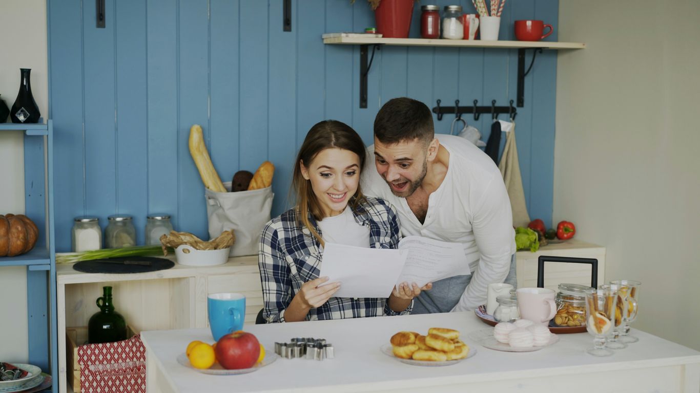 Couple looking at papers in a bright kitchen.