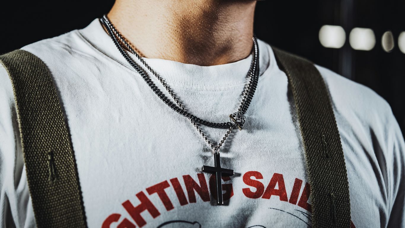 a man wearing a white shirt and a cross necklace