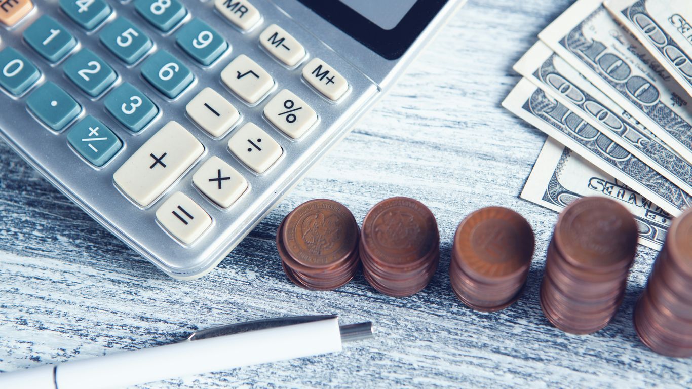 a calculator, pen, and money on a table