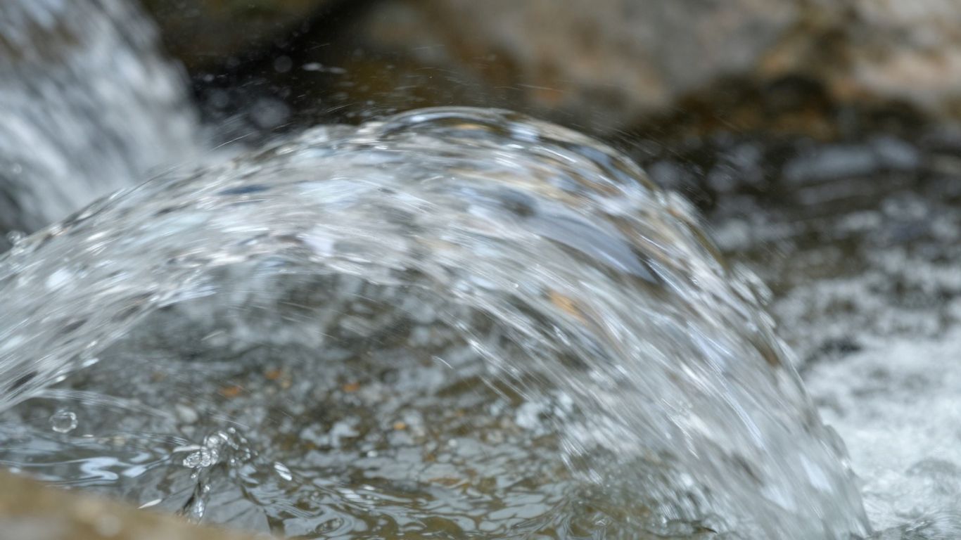Fließendes Wasser in Nahaufnahme mit Lichtreflexionen.