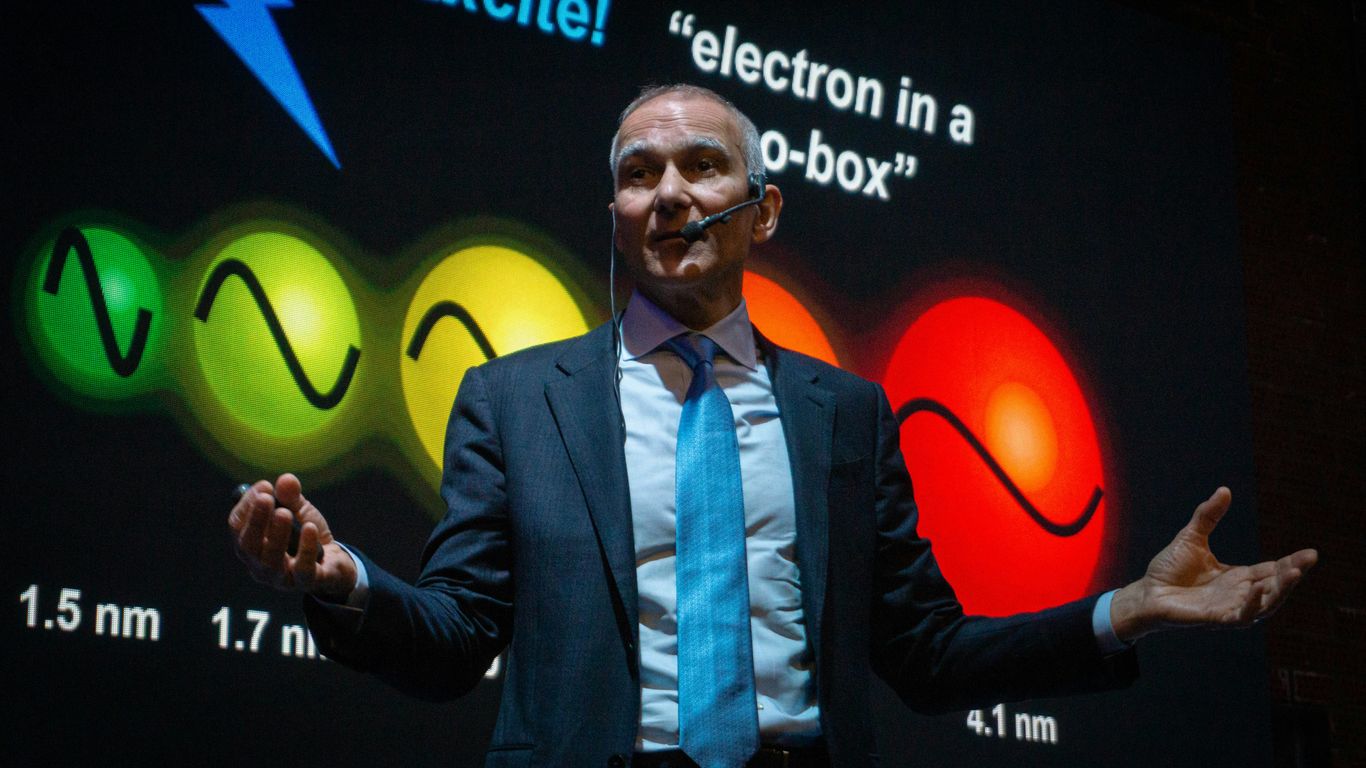 Man in suit presents science concept with colorful graphics.