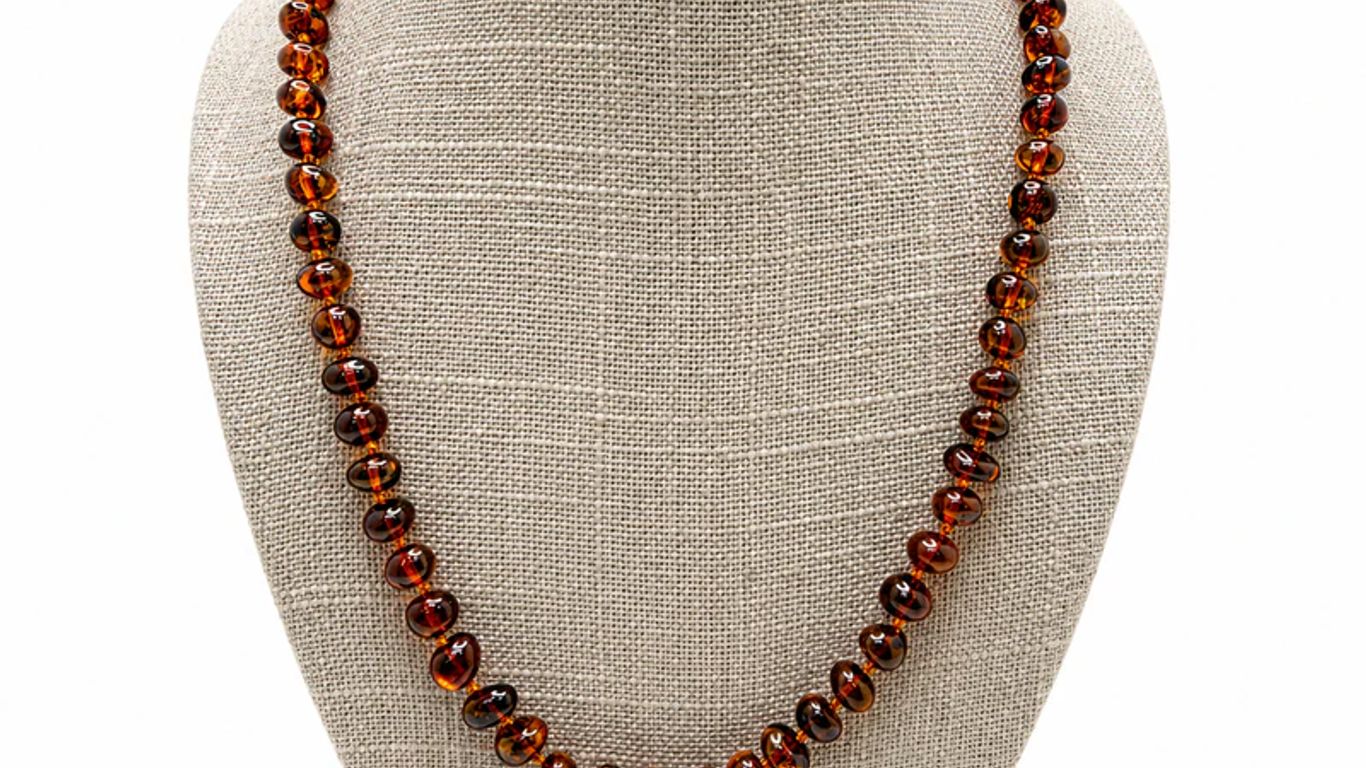 A necklace with polished amber beads on a display bust.