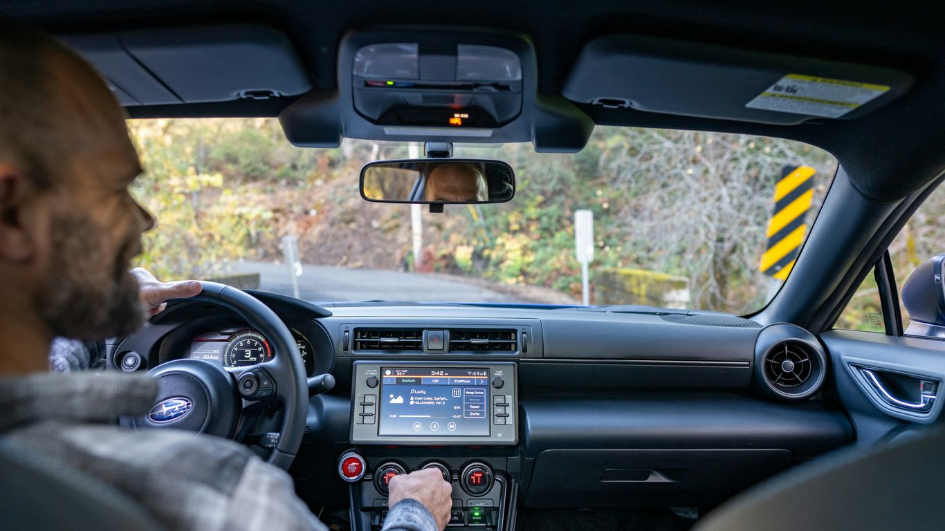 A man driving a car with a gps device in his hand