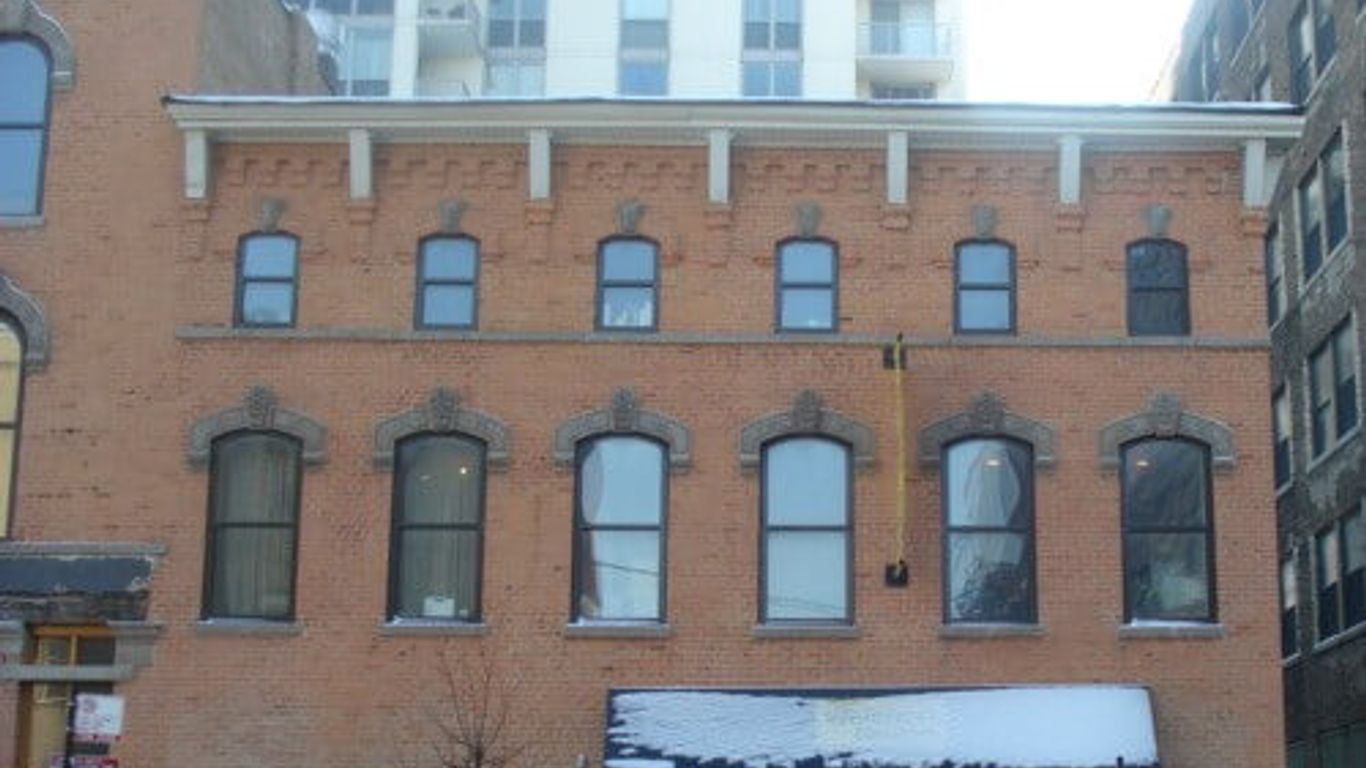 A brick building with many windows and a modern building behind it.