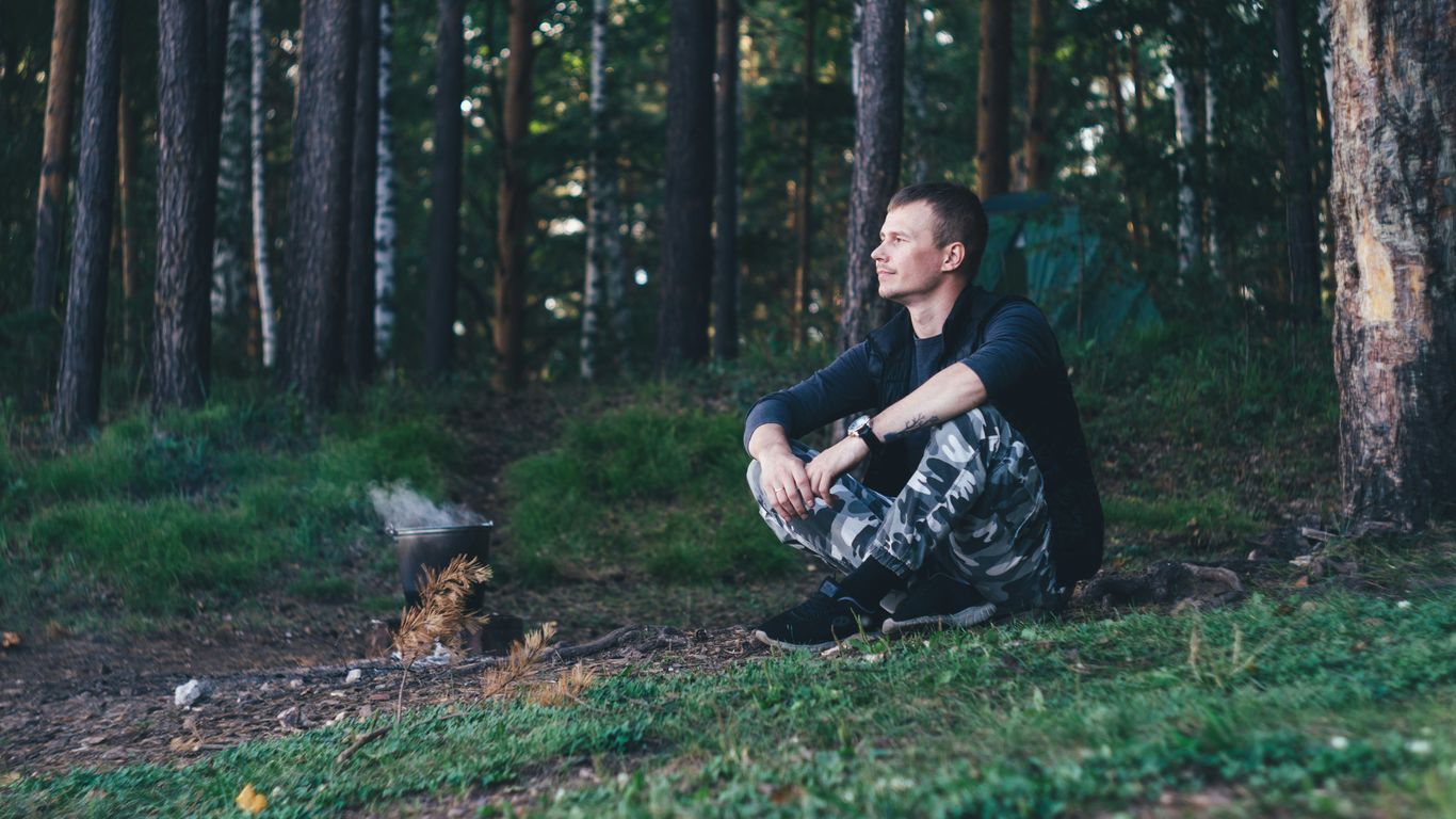 woman in black and white floral long sleeve shirt lying on green grass field
