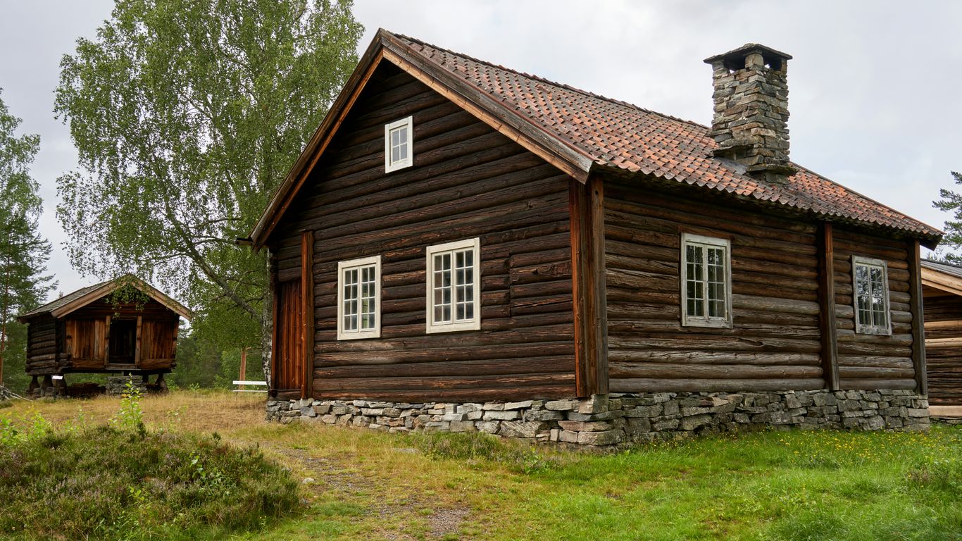 Rustic wooden cabin with stone foundation and chimney.