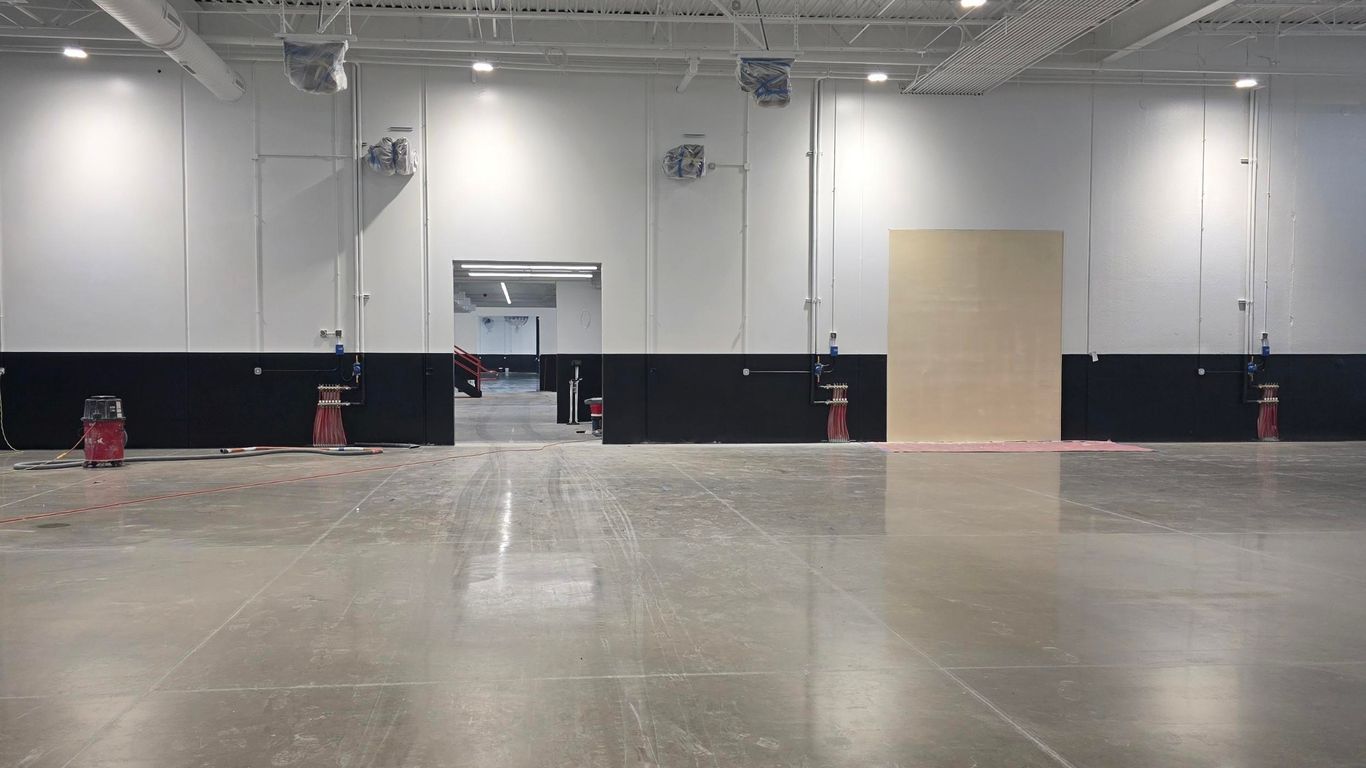Large, empty indoor space with concrete floor and exposed ceiling.