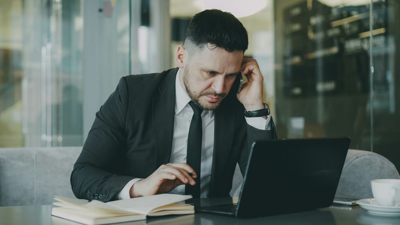 Man in suit working on laptop at a table.