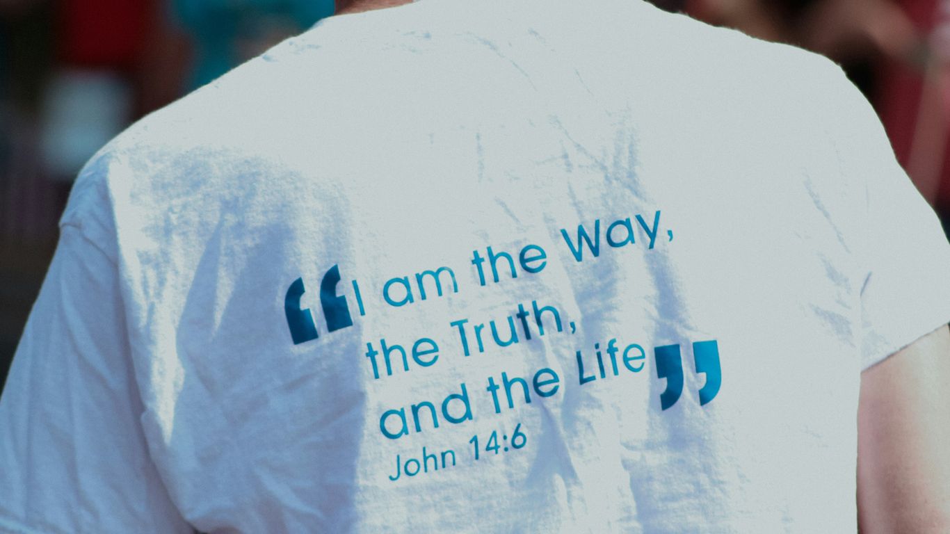 a man wearing a white shirt with a bible verse on it