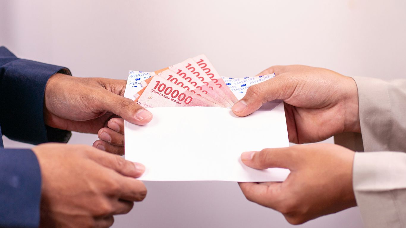 A person is giving money in an envelope.