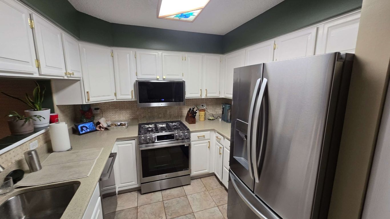 A modern kitchen with white cabinets and stainless steel appliances.