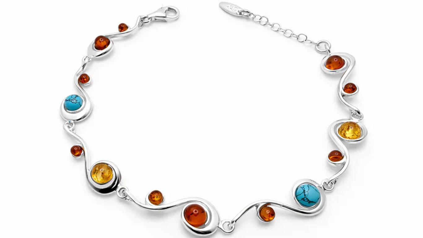 A silver bracelet with amber and turquoise stones in a swirling design.