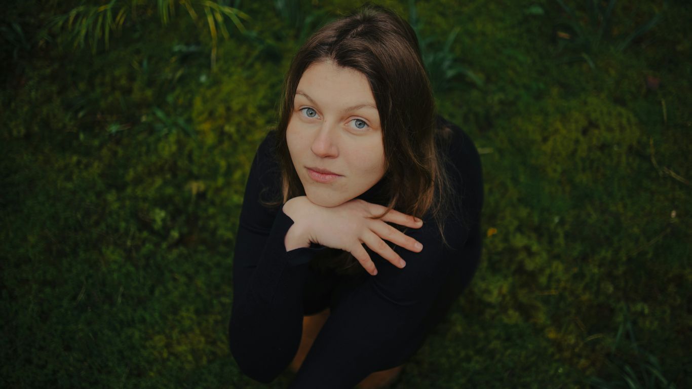 Young woman looking up from grassy field