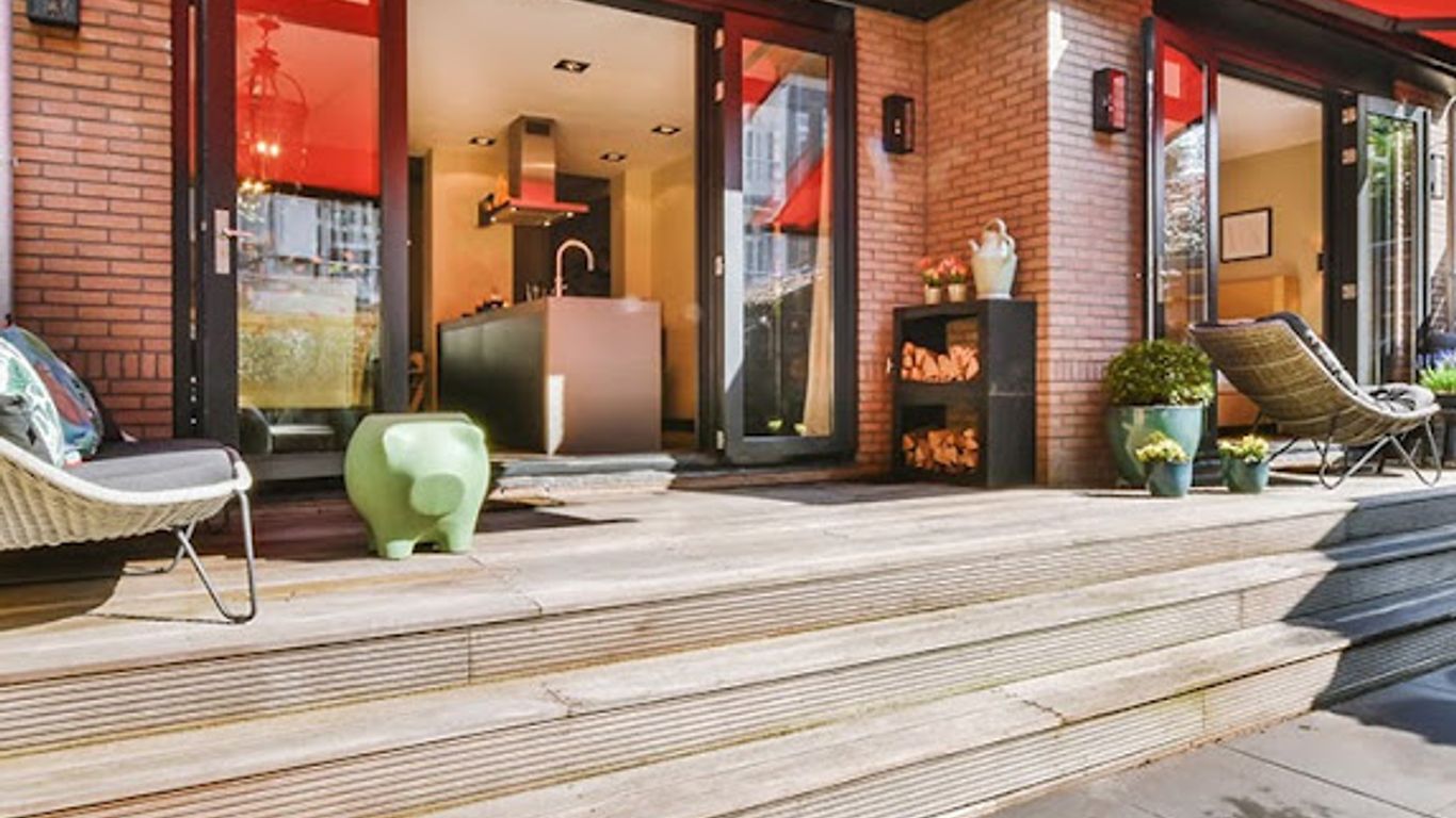 Modern patio with red awning, outdoor seating, and kitchen visible inside.