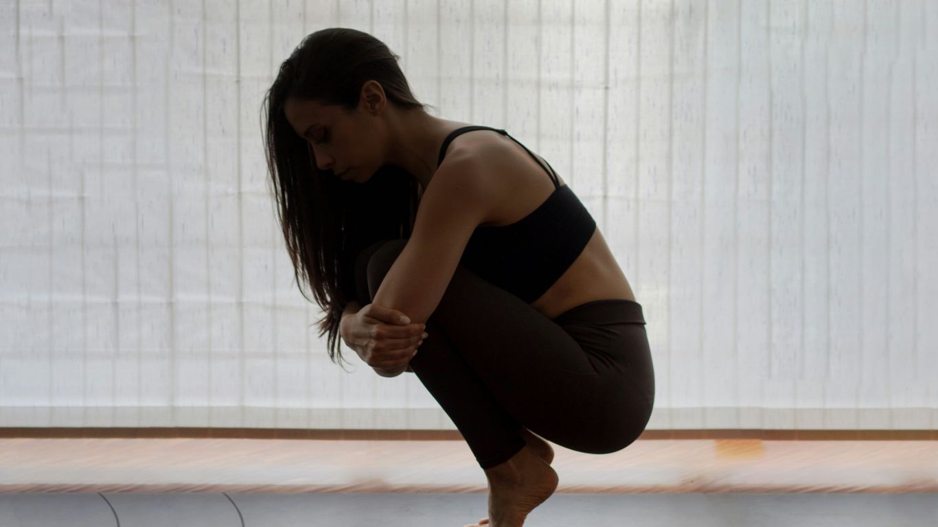 woman in black tank top and black leggings kneeling on floor