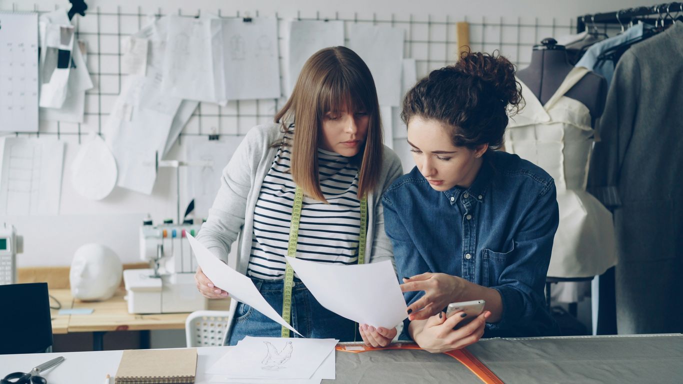 Two designers discuss a paper in a workshop.