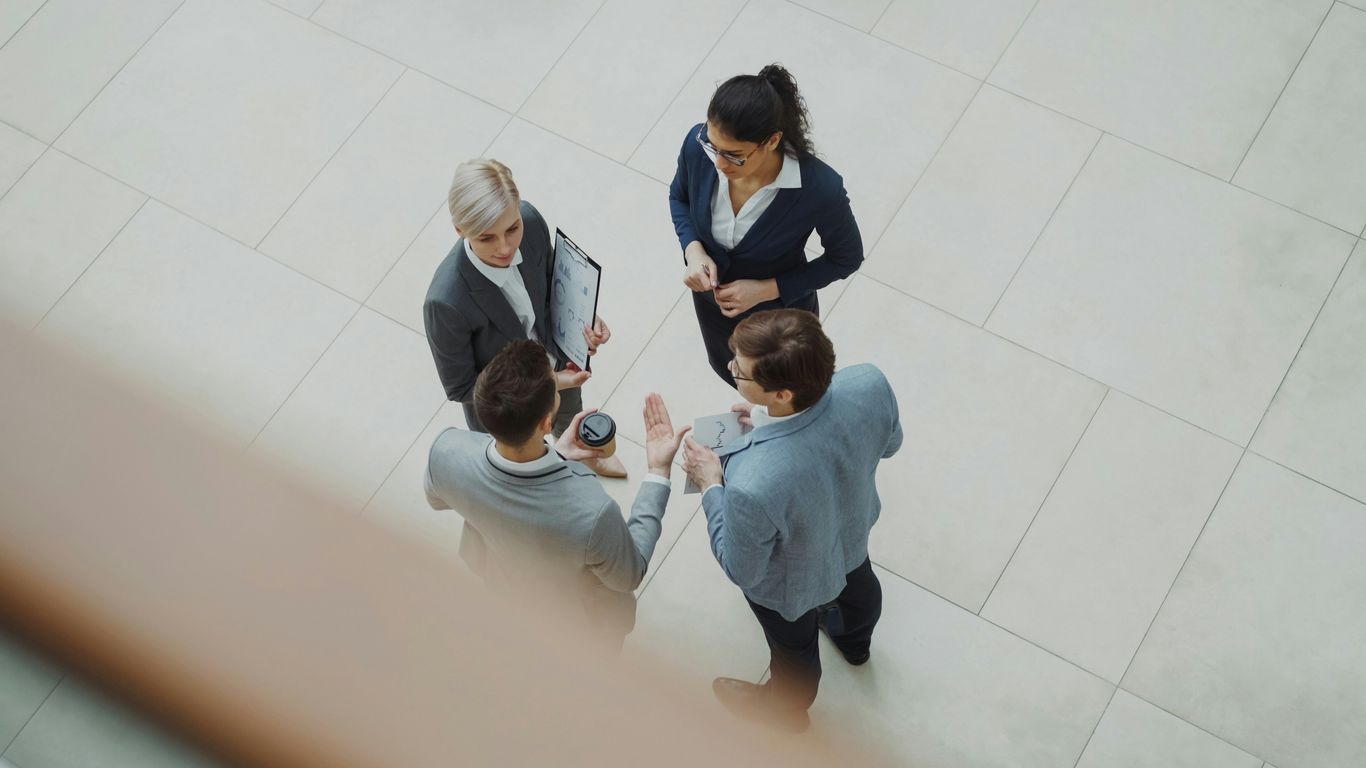 Cuatro empresarios hablando en el lobby de una oficina moderna.