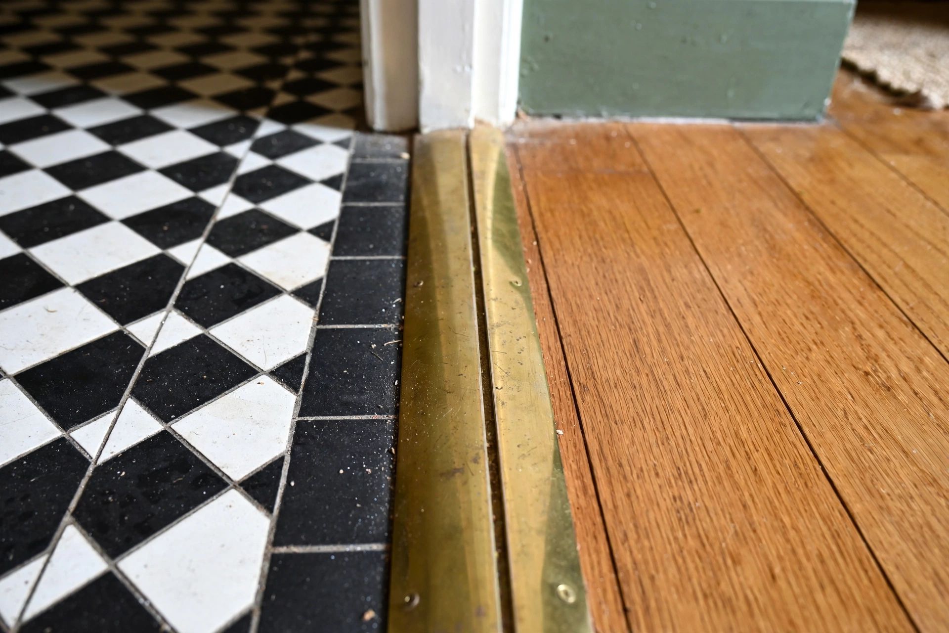 A close-up of a neatly fitted threshold between hallway flooring and an adjoining room in a Bristol home