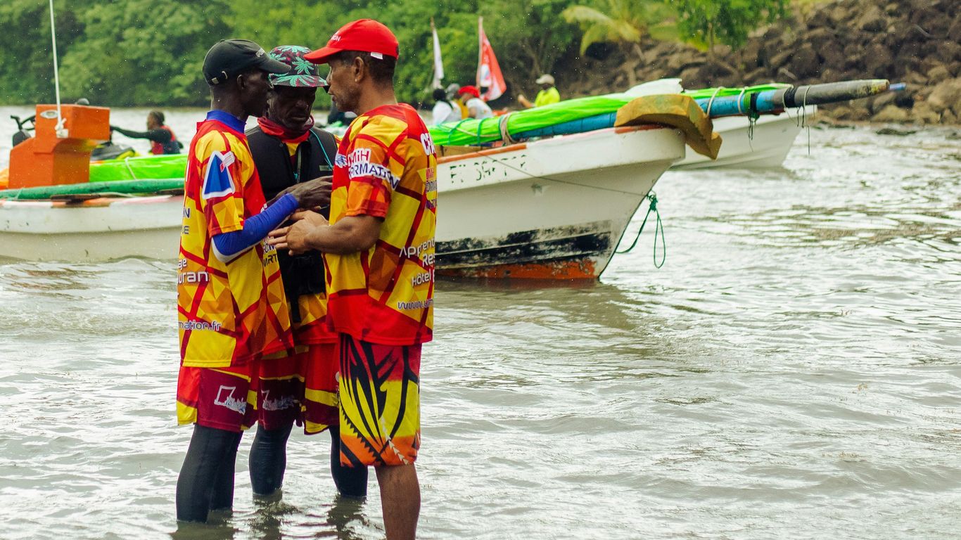 a group of men in life jackets holding a fish in a river