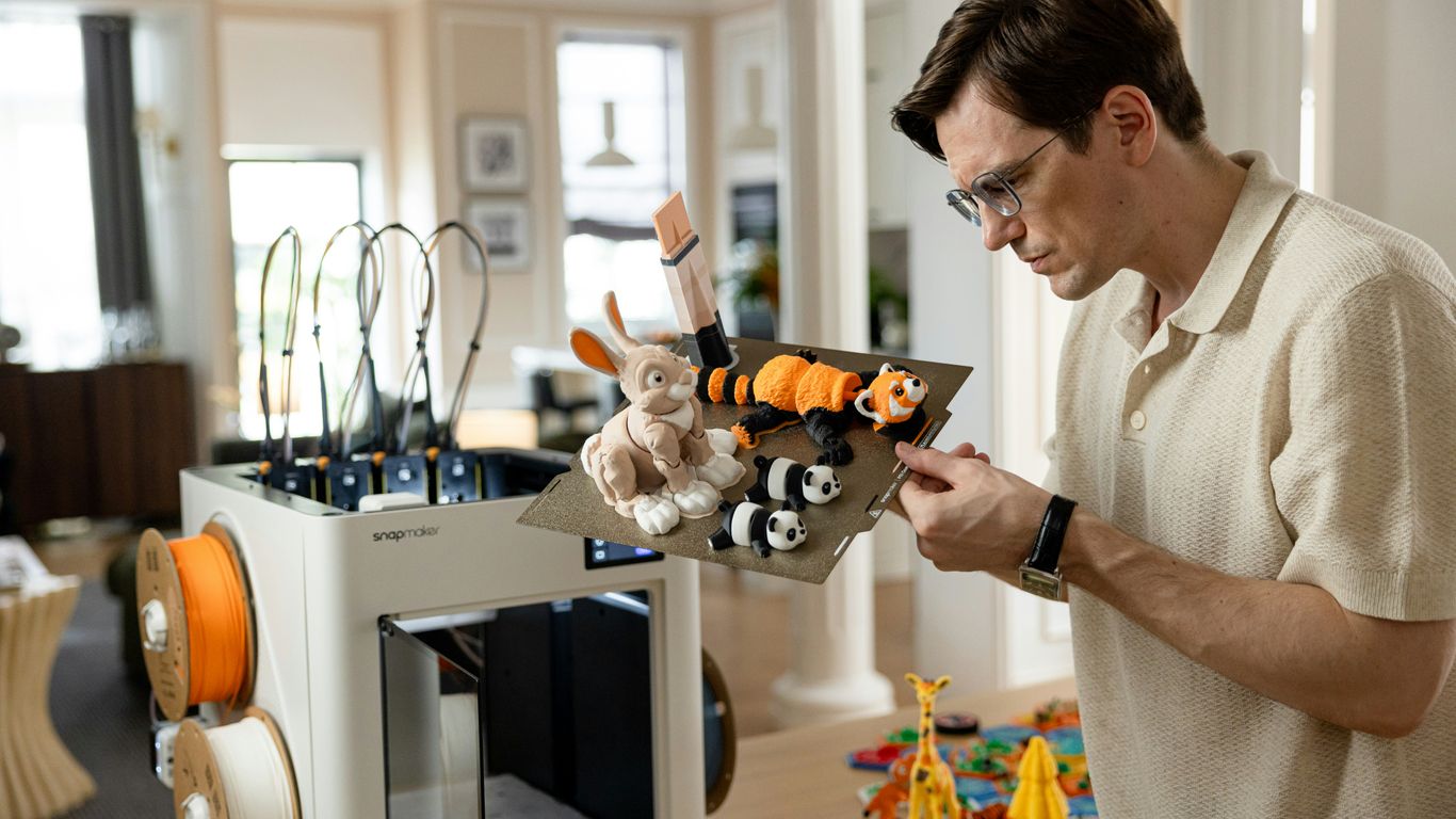 Man working with 3D printer and toys