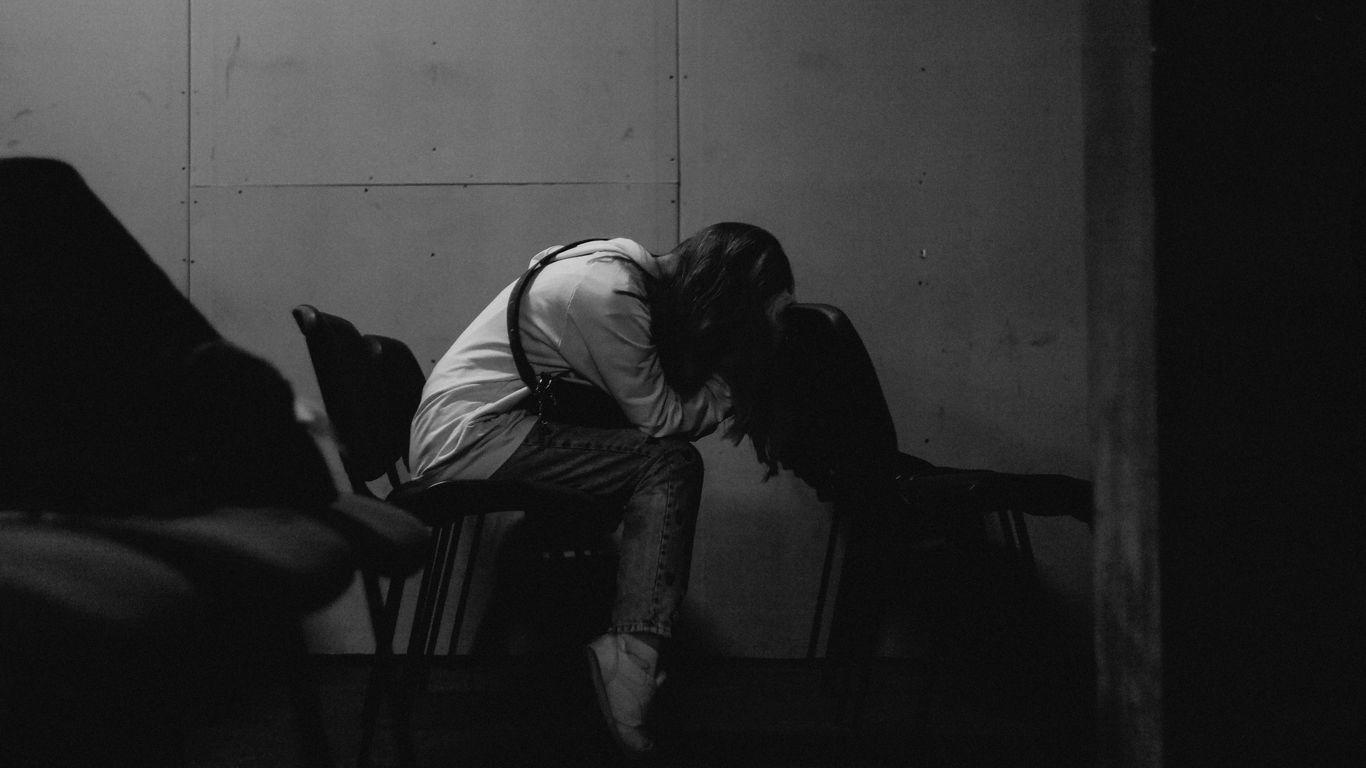 A person sits alone, head in hands.