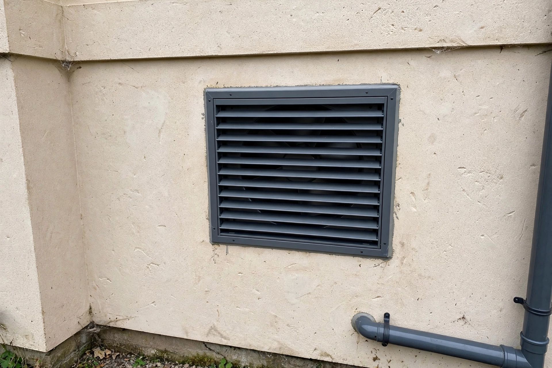 Finished extractor fan wall opening with a louvre fitted on a rendered exterior wall