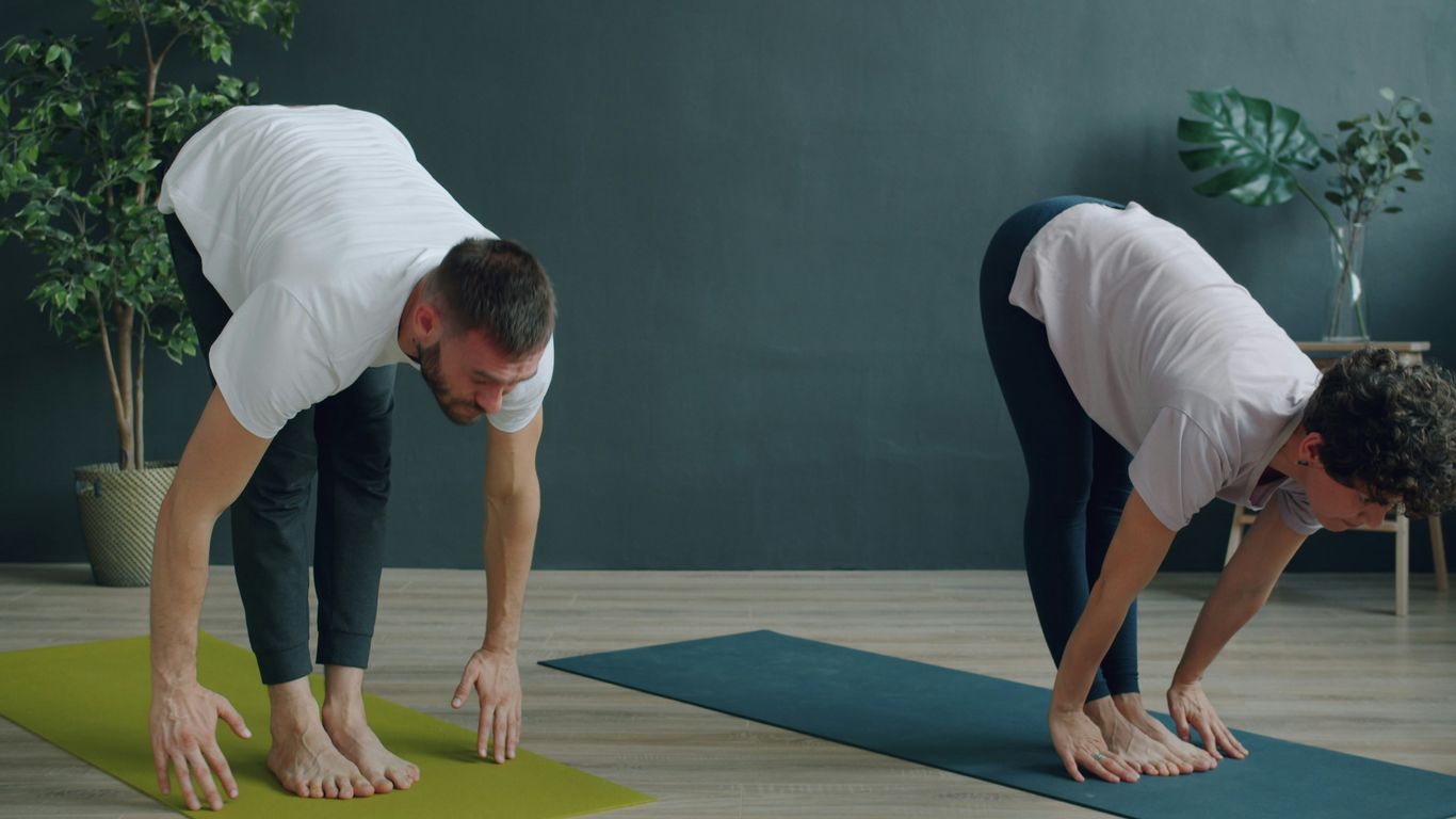 Two people doing yoga on mats in a room