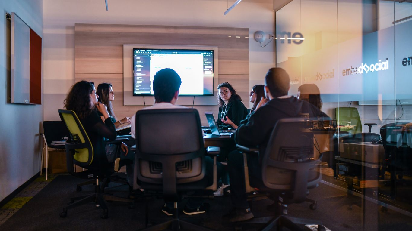 a group of people sitting in chairs in front of a projector screen