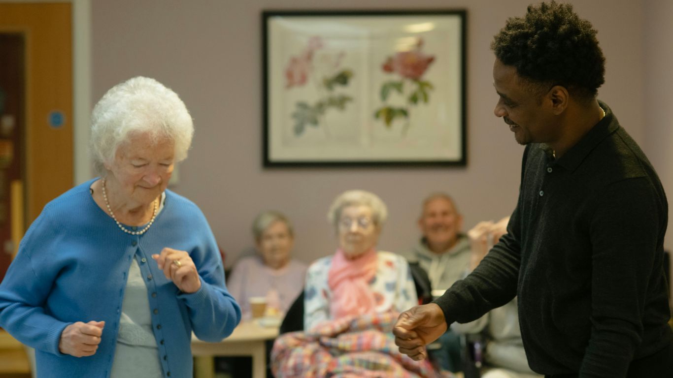 Elderly woman dancing with a man in a room.