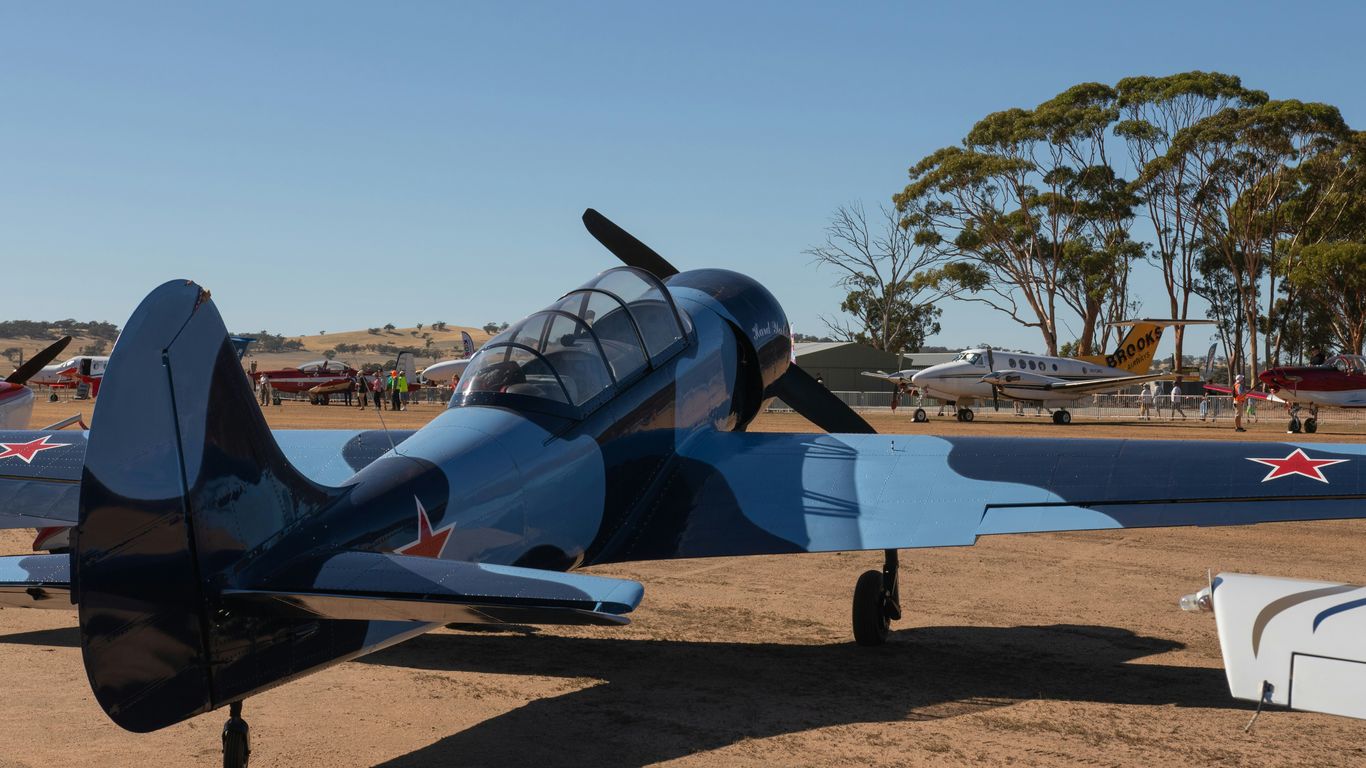 An early aircraft resting beside grass airfield
