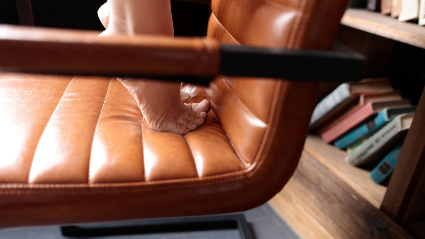 Bare feet standing on a leather chair