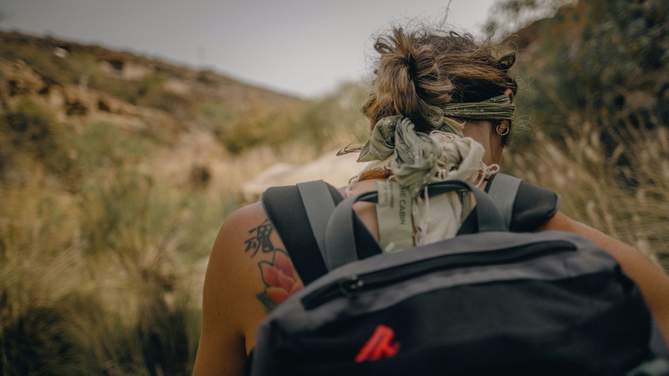 a woman with a bandana on her head walking through a field