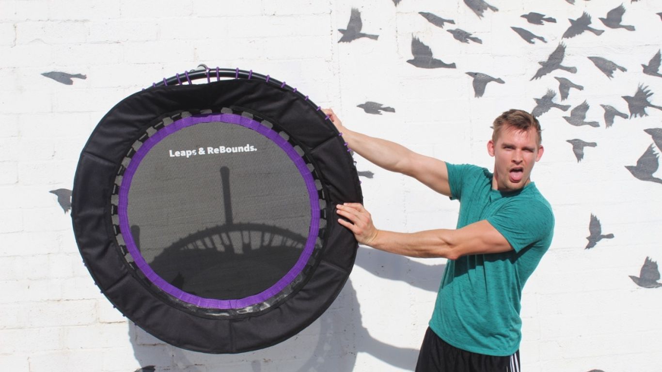 Person holding trampoline against wall with bird silhouettes, looking surprised.