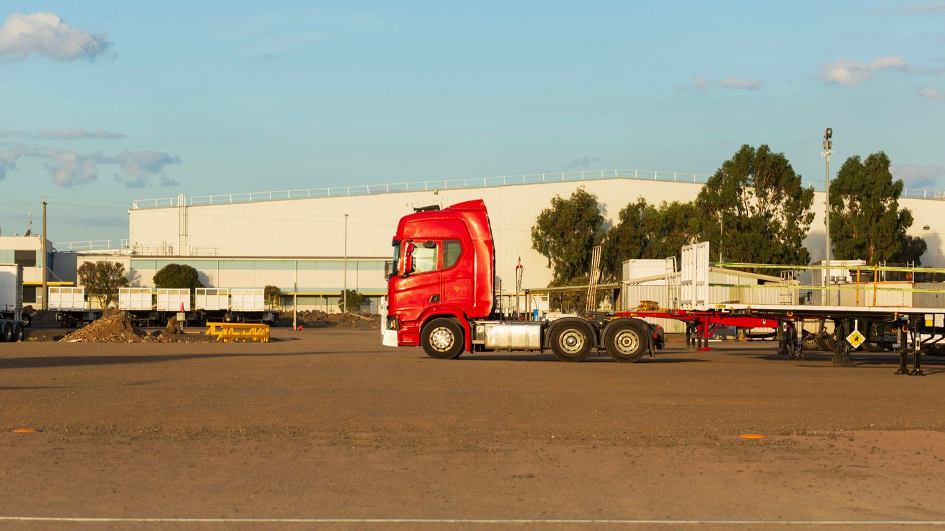 Camión semirremolque rojo estacionado en un lote industrial