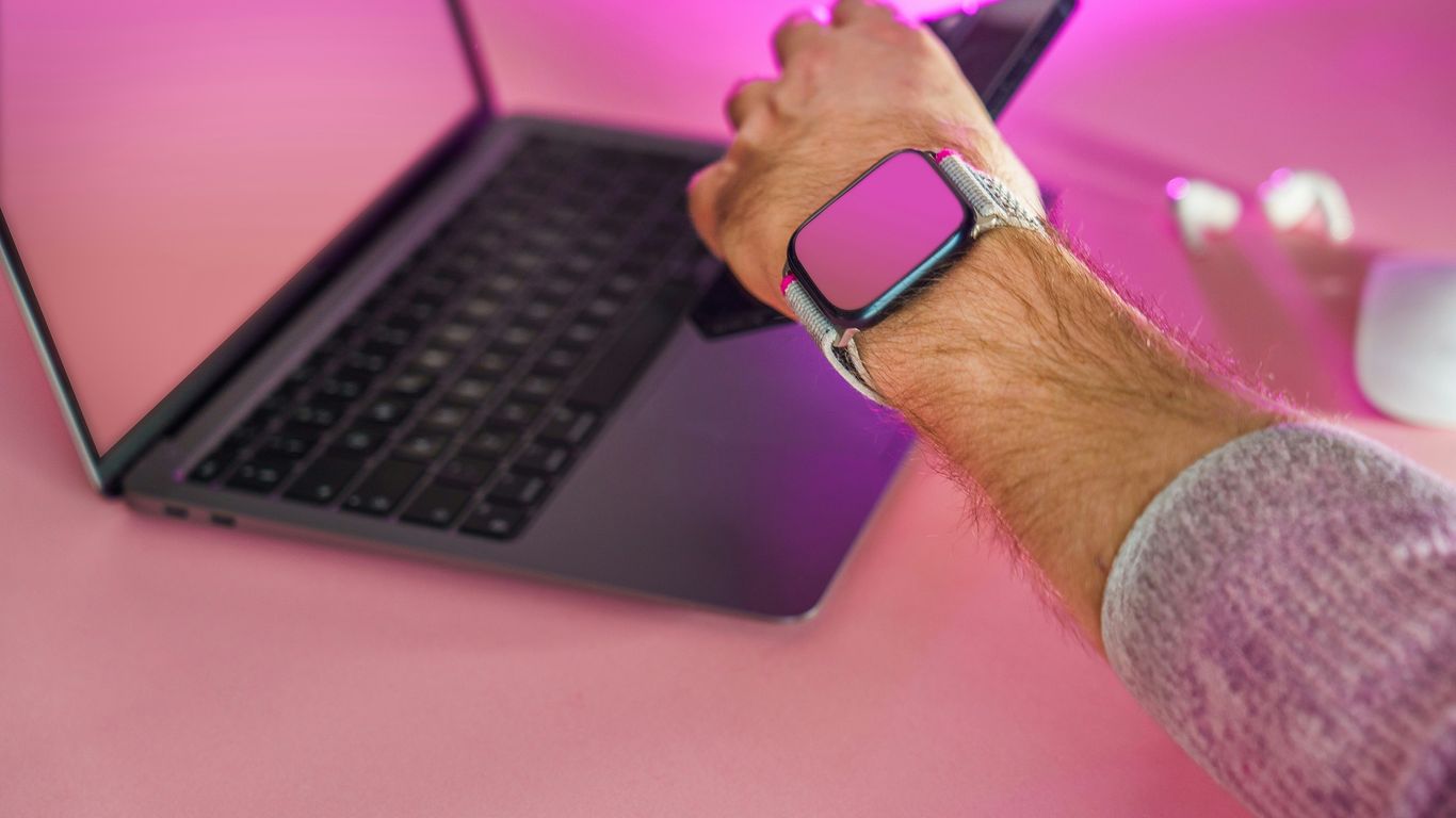 a man holding a smart phone while using a laptop