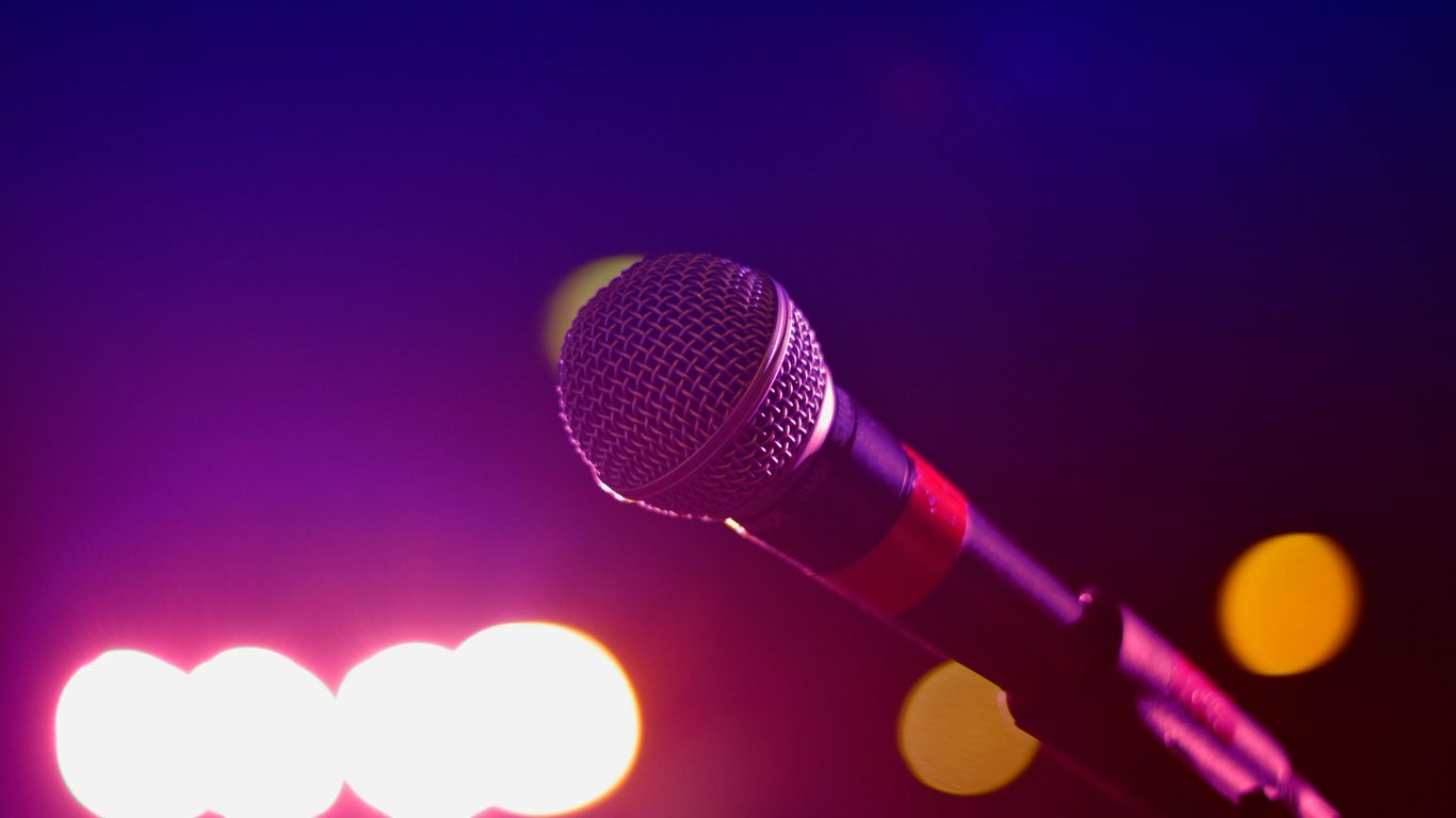 A close-up of a microphone with colorful blurred lights.
