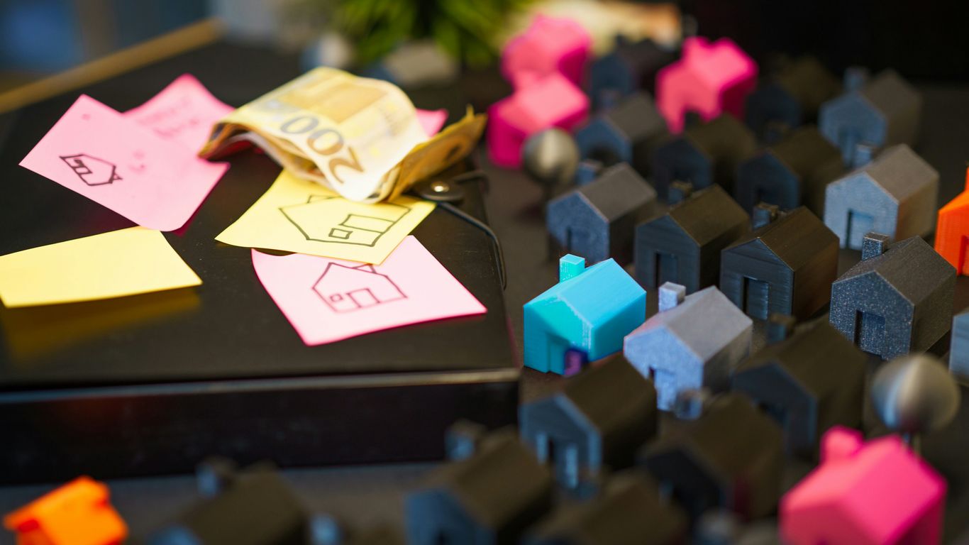Miniature houses with euro banknotes and sticky notes.