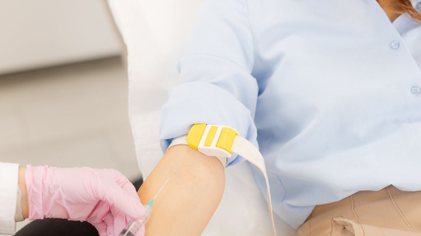 Medical professional drawing blood from a smiling person's arm.