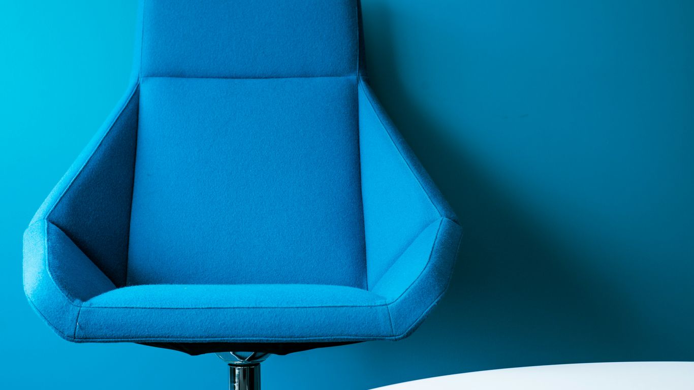 blue padded swivel chair leaning on wall