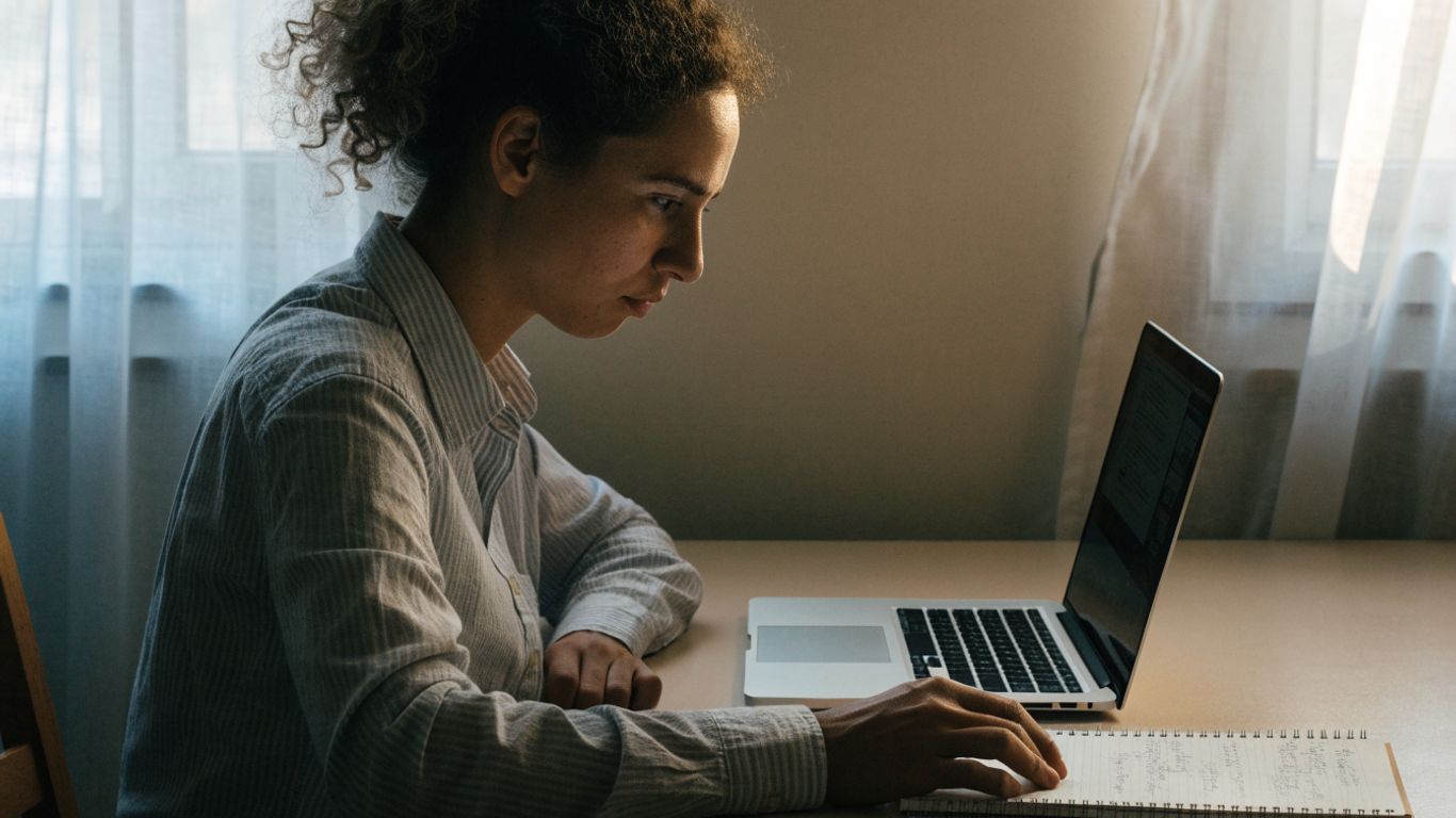 A trader checking account balances beside a laptop