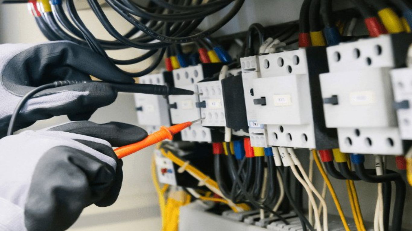 Electrician testing electrical panel with multimeter.