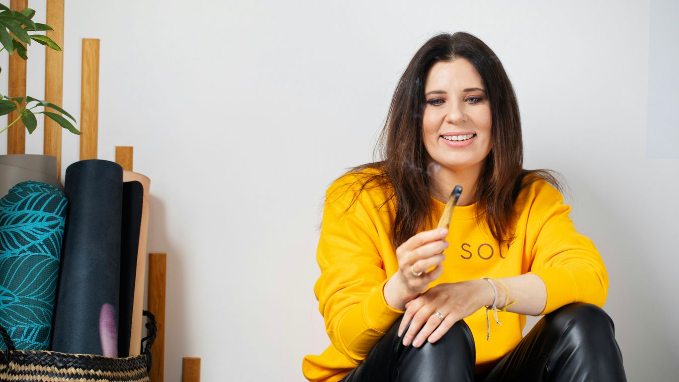 Woman in yellow sweatshirt holds incense stick