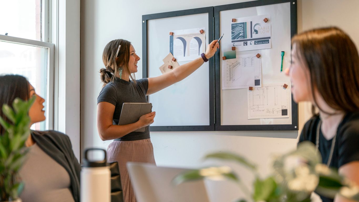 a group of women sitting around a table working on a project