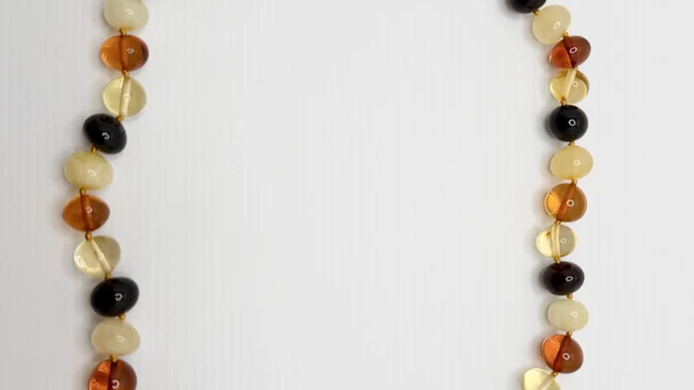 A necklace with polished amber beads of various colors on a white background.
