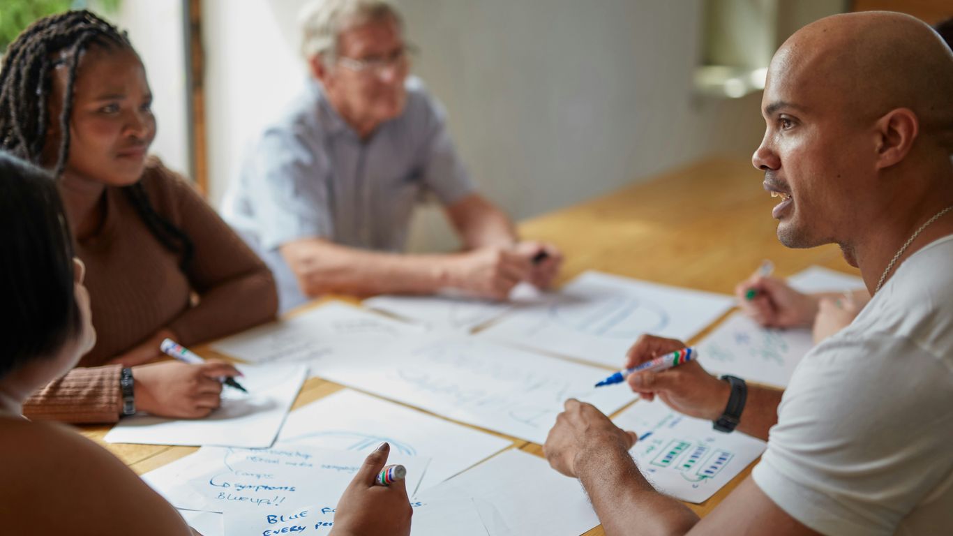 People are collaborating on papers at a table.