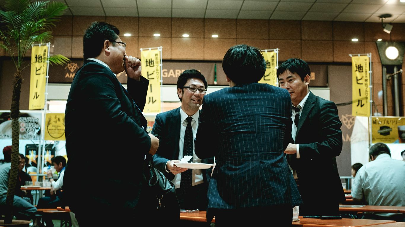 group of people standing in front of brown wooden table