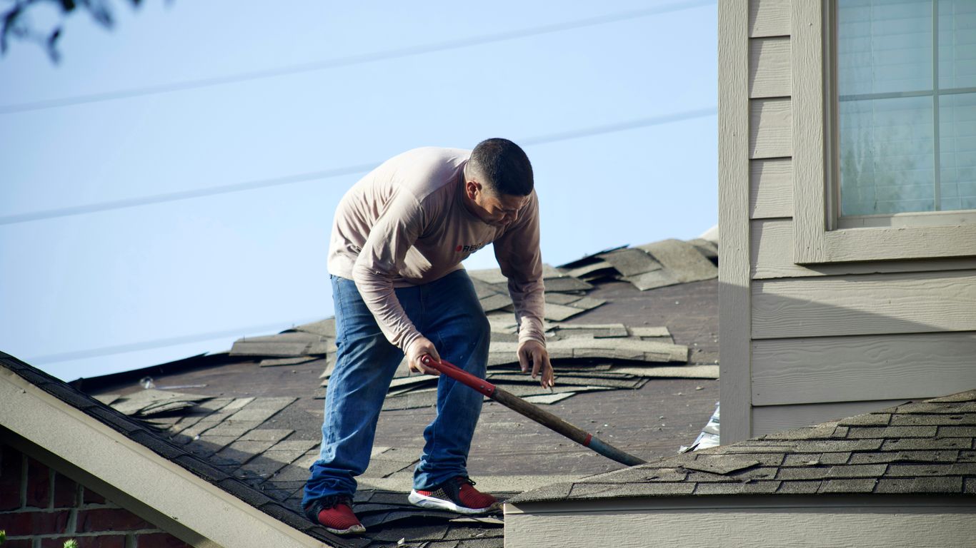 a man with a hammer on top of a roof