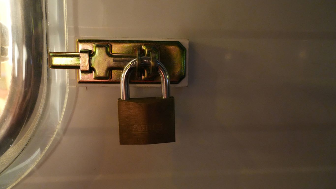 A brass padlock secures a metal latch.