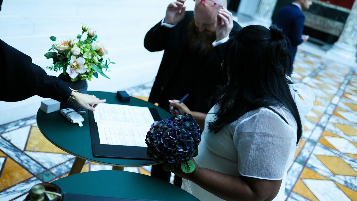Couple signing marriage certificate with officiant present